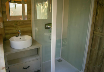 Badkamer van een luxe Safari lodge op Vakantiepark De Boshoek in Nederland, met douche, wastafel en spiegel.