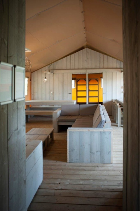 Interior de una villa de tienda safari con mobiliario de madera en Holiday park De Boshoek, Países Bajos.
