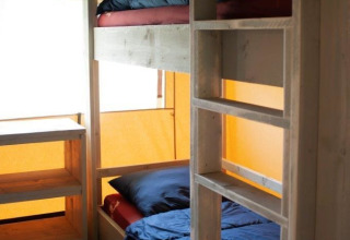 Binnenaanzicht van Safari Villa tent met stapelbedden en houten planken in Vakantiepark De Boshoek, Nederland.