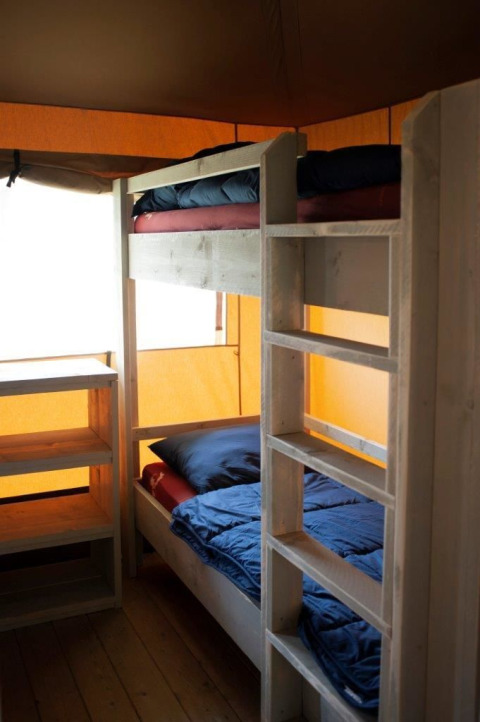 Binnenaanzicht van Safari Villa tent met stapelbedden en houten planken in Vakantiepark De Boshoek, Nederland.