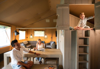 Gezin in een Safari House tent bij Vakantiepark De Boshoek, Nederland, kind speelt in de hoogslaper.