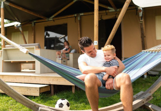 Vader en zoon genieten in een hangmat bij een safaritent in De Boshoek vakantiepark, Nederland.