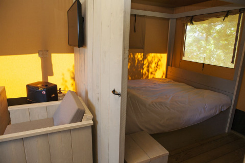 Binnenzicht van een Safari House tent op vakantiepark De Boshoek in Nederland met bed en zitje.
