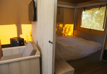 Vista interna della tenda Safari House al parco vacanze De Boshoek nei Paesi Bassi con letto.