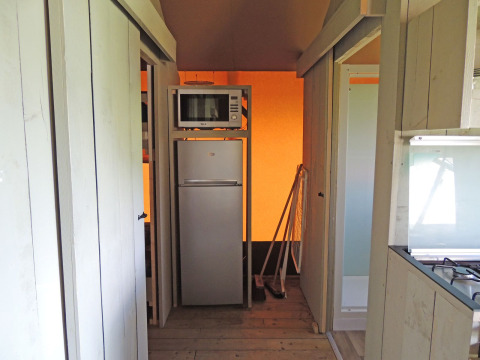 Eine kleine Küchenzeile mit Kühlschrank und Mikrowelle im Safari-Zelt im Ferienpark De Boshoek, Niederlande.