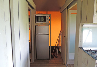 A compact kitchen area with fridge and microwave inside a Safari House tent at Holiday park De Boshoek, Netherlands.