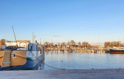 Husbaad De Zwerver ved Marina Parcs Naarden i Holland, fortøjet ved havnen på en klar, solrig dag.