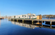 La casa flotante De Zwerver amarrada en Marina Parcs Naarden, Países Bajos, bajo el cielo despejado.