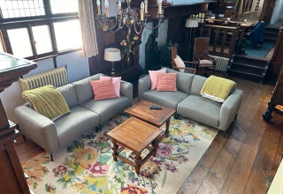 Living room interior on Houseboat De Zwerver at Marina Parcs Naarden, Netherlands, with sofas and floral rug.
