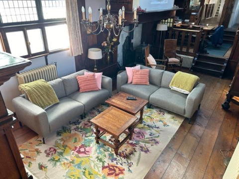 Sala de estar en la casa flotante De Zwerver en Marina Parcs Naarden, Países Bajos, con sofás y alfombra colorida.