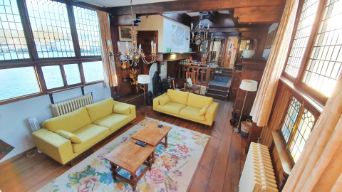 Woonkamer op de woonboot De Zwerver bij Marina Parcs Naarden, Nederland, met gele zetels en houten details.