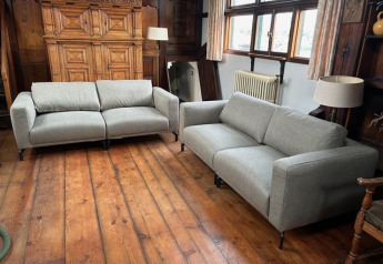 Deux canapés gris dans le salon de Houseboat De Zwerver à Marina Parcs Naarden, Pays-Bas.