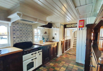 Acogedora cocina de la casa flotante De Zwerver en Marina Parcs Naarden, Países Bajos, con decoración clásica.