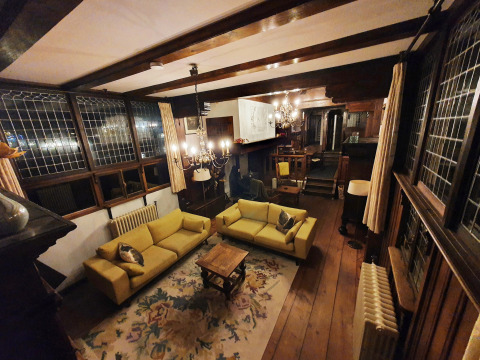 Cozy living room inside Houseboat De Zwerver at Marina Parcs Naarden, Netherlands, with yellow sofas and wood beams.
