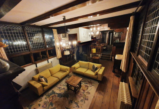 Sala de estar en la casa flotante De Zwerver en Marina Parcs Naarden, Países Bajos, con sofás amarillos y madera.