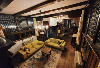 Cozy living room inside Houseboat De Zwerver at Marina Parcs Naarden, Netherlands, with yellow sofas and wood beams.