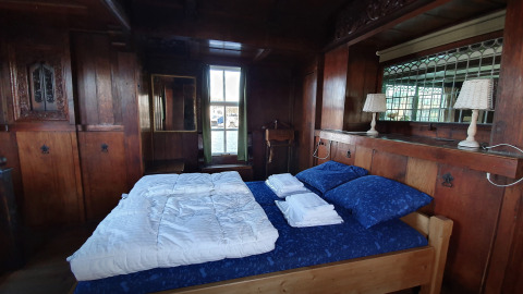 Dormitorio con paneles de madera en Houseboat De Zwerver en Marina Parcs Naarden, Países Bajos, cama doble visible.