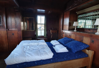 Dormitorio con paneles de madera en Houseboat De Zwerver en Marina Parcs Naarden, Países Bajos, cama doble visible.