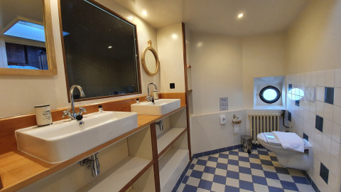 Baño con doble lavabo, espejos y aseo en el Houseboat De Zwerver en Marina Parcs Naarden, Países Bajos.