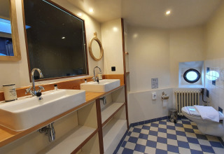 Salle de bain avec double vasque, miroirs et WC sur Houseboat De Zwerver à Marina Parcs Naarden, Pays-Bas.