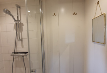 Douche met witte tegels, spiegel en haakjes op de Houseboat De Zwerver in Marina Parcs Naarden.