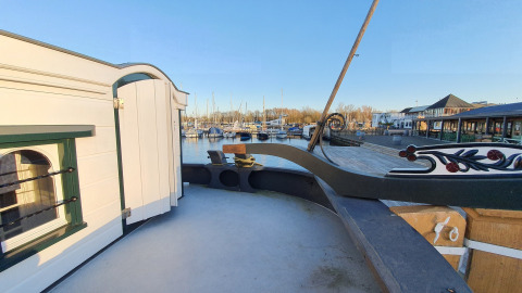 Uitzicht vanaf Houseboat De Zwerver bij Marina Parcs Naarden, met boten in de haven en gebouwen erbij.