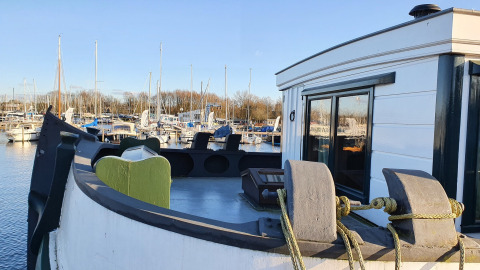 Vista desde el Houseboat De Zwerver en Marina Parcs Naarden, Países Bajos, con muelle y barcos al fondo.