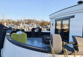 Vue depuis Houseboat De Zwerver à Marina Parcs Naarden, Pays-Bas, avec marina et bateaux à l'arrière-plan.