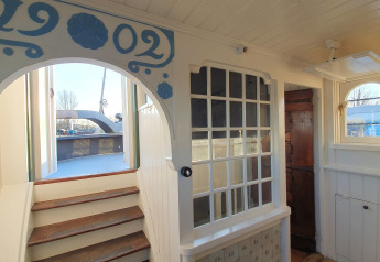 Interior de la casa flotante De Zwerver en Marina Parcs Naarden, Países Bajos, con escaleras al exterior.