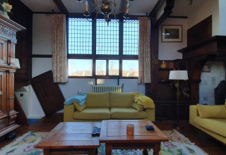 Living room on Houseboat De Zwerver at Marina Parcs Naarden, Netherlands, with yellow sofas and large windows.