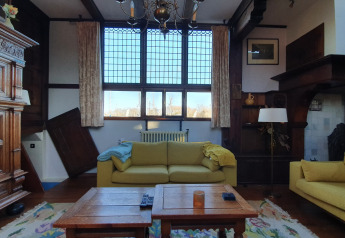 Living room on Houseboat De Zwerver at Marina Parcs Naarden, Netherlands, with yellow sofas and large windows.