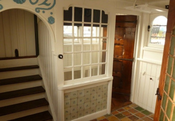 Bright and charming interior of Houseboat De Zwerver at Marina Parcs Naarden, Netherlands, wooden staircase visible.