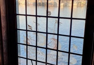 Blick durch ein bleiverglastes Fenster im Hausboot De Zwerver mit Schiffsmotiv bei Marina Parcs Naarden.