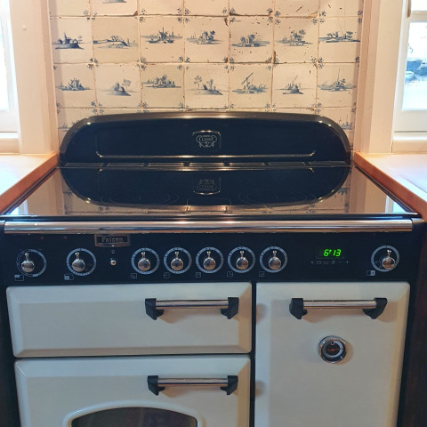 Cocina retro en una casa flotante, con salpicadero de azulejos y placa moderna en Naarden, Países Bajos.