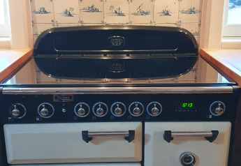 Cocina retro en una casa flotante, con salpicadero de azulejos y placa moderna en Naarden, Países Bajos.