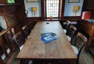 Een houten tafel met stoelen in een knusse ruimte op houseboat De Zwerver in Marina Parcs Naarden, Nederland.