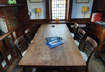 A wooden table with chairs in a cozy room aboard houseboat De Zwerver at Marina Parcs Naarden, Netherlands.