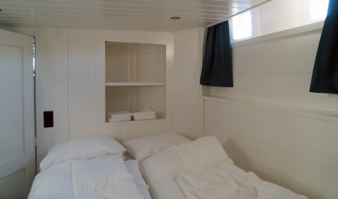 Soveværelse på Houseboat De Zwerver ved Marina Parcs Naarden, med to senge og lyse vægge.