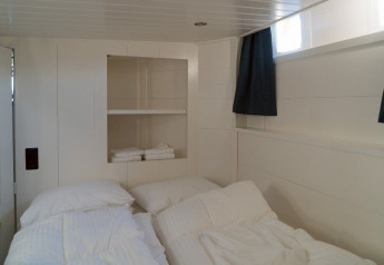 Chambre à bord du Houseboat De Zwerver à Marina Parcs Naarden, aux Pays-Bas, avec deux lits simples.