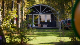 Una moderna cabaña Vechtdallodge en Kampeerdorp de Zandstuve, Países Bajos, rodeada de vegetación.