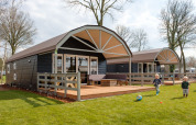Two children play on the grass in front of Vechtdallodge cabins at Kampeerdorp de Zandstuve in the Netherlands.