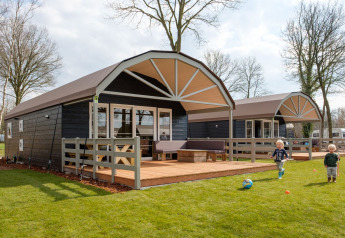 Due bambini giocano sull’erba davanti alle lodge Vechtdallodge al Kampeerdorp de Zandstuve, Paesi Bassi.