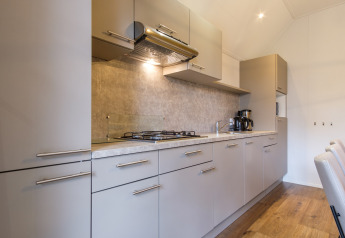 Cucina moderna nella Vechtdallodge al Kampeerdorp de Zandstuve, Paesi Bassi, con fornello e armadietti.