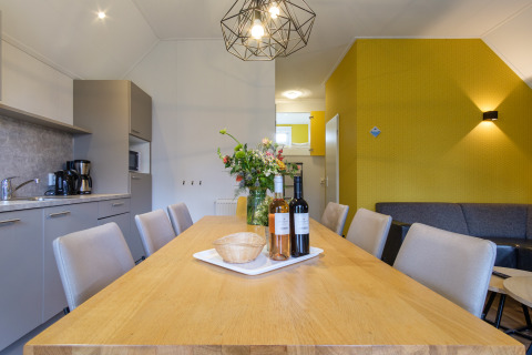 Moderne eetruimte in Vechtdallodge, Kampeerdorp de Zandstuve, Nederland, met houten tafel en bloemen.