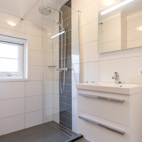Baño moderno con ducha de vidrio, lavabo y espejo amplio en Vechtdallodge, Kampeerdorp de Zandstuve, Países Bajos.