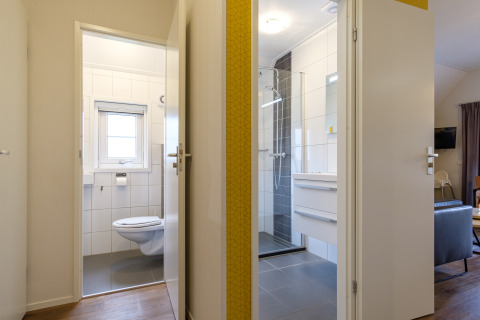 Puertas abiertas al baño y aseo en Vechtdallodge de Kampeerdorp de Zandstuve, Países Bajos, con estilo moderno.