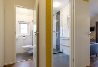 Puertas abiertas al baño y aseo en Vechtdallodge de Kampeerdorp de Zandstuve, Países Bajos, con estilo moderno.