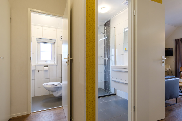Open deuren naar badkamer en toilet in de Vechtdallodge bij Kampeerdorp de Zandstuve, Nederland, modern interieur.
