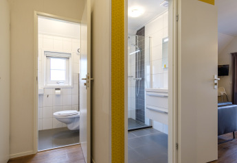 Open doors to bathroom and toilet in Vechtdallodge at Kampeerdorp de Zandstuve, Netherlands, with modern decor.