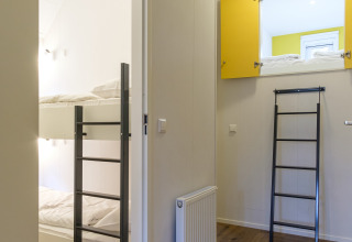 Indvendigt foto af Vechtdallodge på Kampeerdorp de Zandstuve, Holland, med køjesenge og stige i rummet.